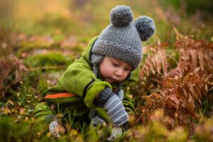 Child doing autumn activities for kids in the forest with a childminder