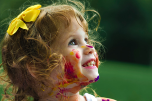 little girl smiling with paint all over her face