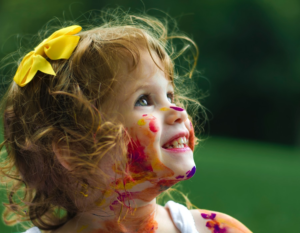 little girl smiling with paint all over her face