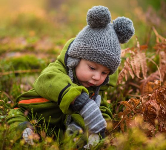 Child doing autumn activities for kids in the forest with a childminder