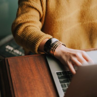 woman working on laptop in mustard yellow jumper