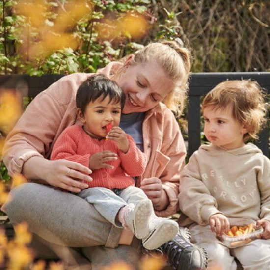 childcarer with two children eating - opt