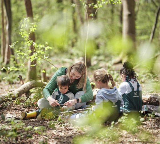 Childminder sitting and playing with children in the forest