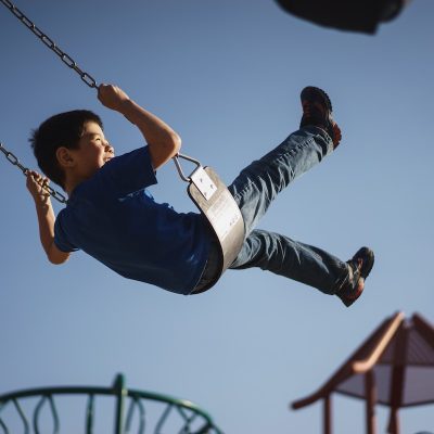 childminder pushing a child on a swing